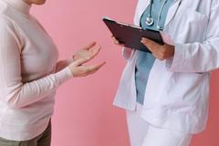 Une femme en consultation discute avec une professionnelle de santé, toutes deux debout.
