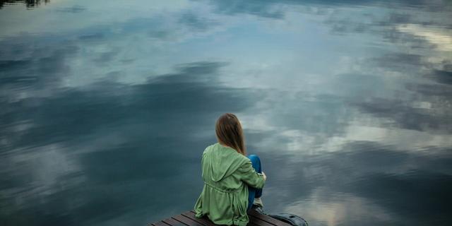 Femme en méditation devant une étendue d'eau