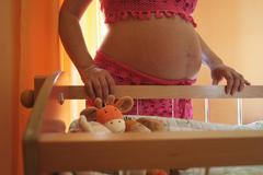 Femme enceinte devant le lit de son futur bébé