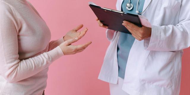 Une femme en consultation discute avec une professionnelle de santé, toutes deux debout.