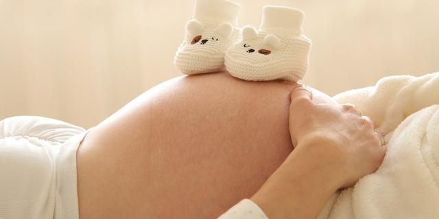 Chaussons de bébé sur le ventre d'une femme enceinte