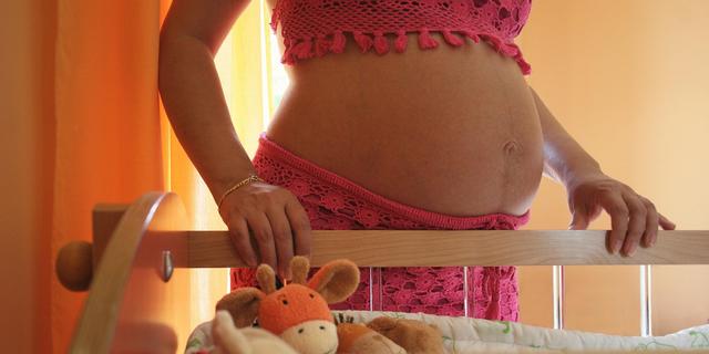 Femme enceinte devant le lit de son futur bébé
