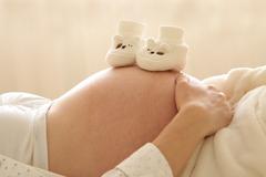 Chaussons de bébé sur le ventre d'une femme enceinte